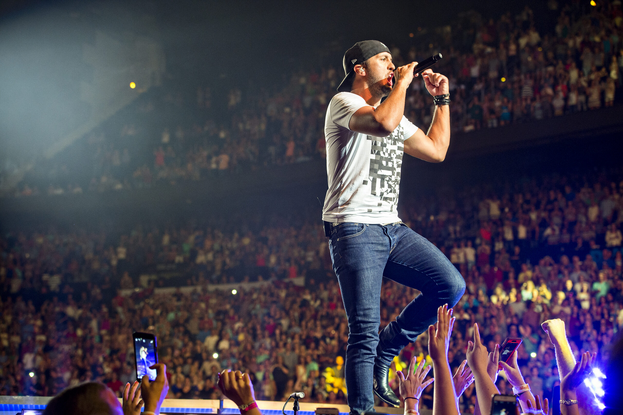 Musician performing on stage at a packed arena concert